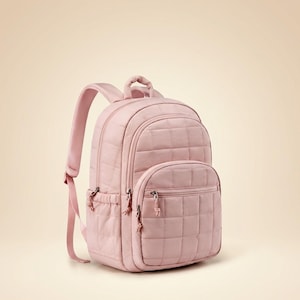 May include: A light pink quilted backpack featuring a large main compartment, a smaller front zippered pocket, and two side pockets. The bag includes adjustable padded shoulder straps, a top carry handle, and silver-toned metal zipper pulls.
