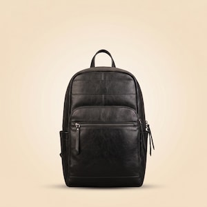 May include: A black backpack featuring a smooth finish, a top handle, and a large front pocket with a horizontal zip. The design includes side pockets and long, thin zip pulls on the main and front compartments, providing a structured appearance.