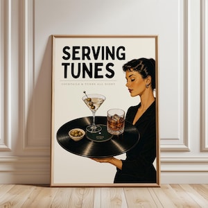 May include: A framed vintage-style print with the text "SERVING TUNES" and "COCKTAILS & TUNES ALL NIGHT". The image features a woman holding a tray with a martini, a whiskey glass, and olives. The tray is a vinyl record.