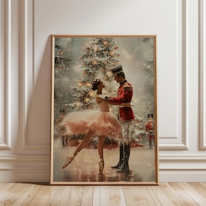 Peut inclure: Une impression d'art encadrée représentant une ballerine en tutu rose clair dansant avec un soldat casse-noisette en uniforme rouge. La scène se déroule devant un sapin de Noël décoré sous la neige, entourée de deux petites figurines casse-noisette.