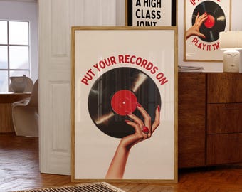 May include: A framed poster with a vintage vinyl record design. The poster features a black record with a red label, held by a hand with red nail polish. Text on the poster reads "PUT YOUR RECORDS ON". Other framed posters are visible.