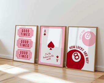 May include: Three framed art prints with a light wood finish. The prints feature pink and red designs with text that reads "GOOD TIMES", "I'm the luckiest in the world", and "HOW LUCKY ARE WE?"