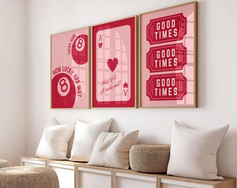 May include: Three framed art prints with a pink background and red graphics. The prints feature a lucky 8 ball, an Ace of Hearts playing card, and three "Good Times" tickets. The prints are in wooden frames and are displayed above a white storage bench.