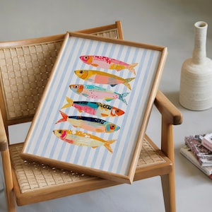May include: A framed art print featuring six stylized fish arranged vertically on a light blue and white striped background. Each fish displays a unique combination of vibrant colors including pink, yellow, orange, blue, and red with textured patterns.