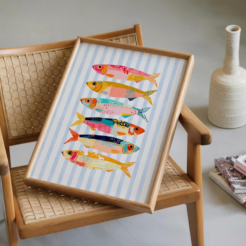 May include: A framed art print featuring six stylized fish arranged vertically on a light blue and white striped background. Each fish displays a unique combination of vibrant colors including pink, yellow, orange, blue, and red with textured patterns.