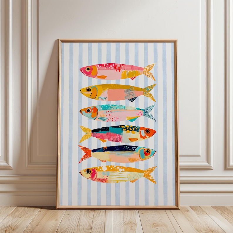 May include: A framed vertical wall art print featuring six stylized fish stacked horizontally. The fish are rendered in vibrant shades of pink, yellow, teal, orange, and blue against a background of vertical light blue and white stripes.