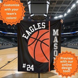 May include: Black basketball banner featuring the word "EAGLES" in white, an orange basketball graphic, and the number "24". The name "MASON" is printed vertically in white. The banner is displayed in a basketball arena. Text reads "Customize with your team's colours!" and "Preview with our online design tool!"