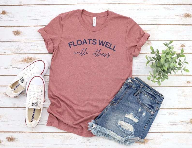 Mauve-colored shirt that says “Floats Well With Others,” great for relaxed summer vibes or matching float squad gear.