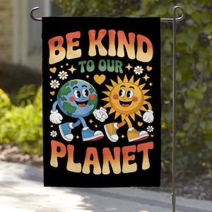 May include: Black garden flag with the text "BE KIND TO OUR PLANET" in orange, yellow, and green. The flag features a cartoon Earth and sun holding hands, surrounded by hearts and flowers.