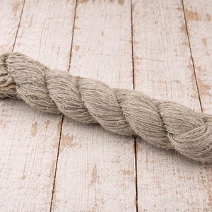 Close view of machine spun nettle wool blend yarn skein on rustic wooden background.