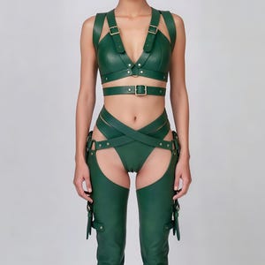 May include: A green leather harness set featuring a bra top, waist belt, and high-waisted bottoms with attached chaps. The set includes adjustable straps and metal buckle closures. The outfit is designed with a form-fitting silhouette.