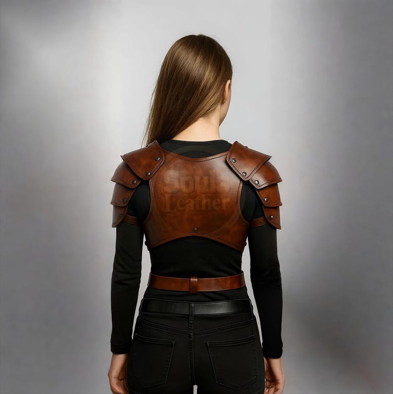 May include: Brown leather shoulder armor with the text "Soul Leather" embossed on the back. The armor has a series of rivets and is worn over a black long-sleeved shirt. A brown belt is also visible.