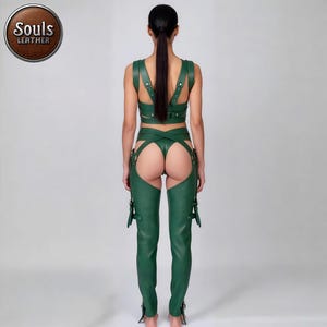 May include: A green leather outfit consisting of a crop top, a thong, and chaps. The crop top has straps over the shoulders and back. The chaps have buckles and straps. The Souls Leather logo is in a brown circle.