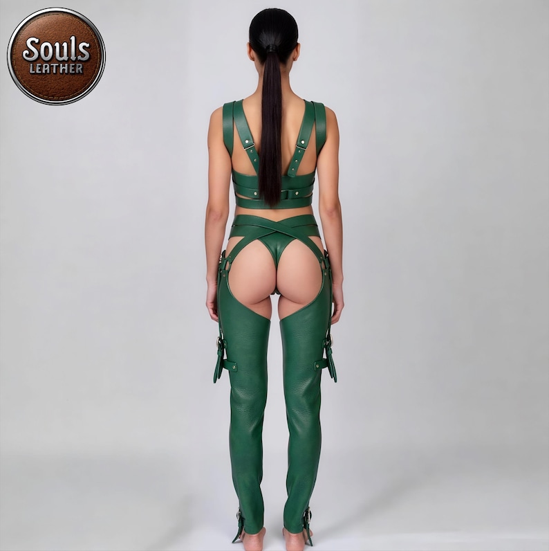 May include: A green leather outfit consisting of a crop top, a thong, and chaps. The crop top has straps over the shoulders and back. The chaps have buckles and straps. The Souls Leather logo is in a brown circle.