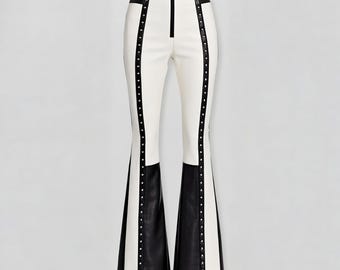 May include: White and black flared pants with a high waist and a zipper closure. The pants feature black panels at the waist and the flared hem, with rows of small silver studs along the side seams.