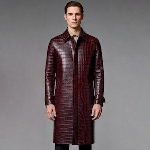 May include: A burgundy, long leather coat with a crocodile skin texture. The coat has a collared neckline and buttoned cuffs. The coat is knee-length and is worn over a light brown collared shirt.