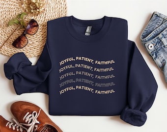 May include: Navy blue sweatshirt with the words "JOYFUL, PATIENT, FAITHFUL" printed in a repeating, arched design. The sweatshirt is paired with brown shoes, sunglasses, and a woven basket.