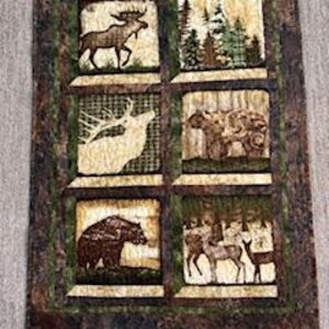 May include: A quilted wall hanging featuring six square panels with wildlife scenes. The panels depict a moose, forest, elk, bison, bear, and deer. The border has a camouflage pattern, and the overall color scheme is earthy tones.