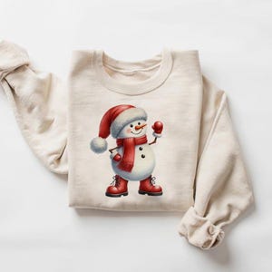 Pu&ograve; includere: Felpa color crema con grafica di pupazzo di neve. Il pupazzo di neve indossa cappello, sciarpa, guanti e stivali rossi. Il disegno &egrave; centrato sul davanti del top a maniche lunghe, perfetto per l'inverno o le festivit&agrave;.