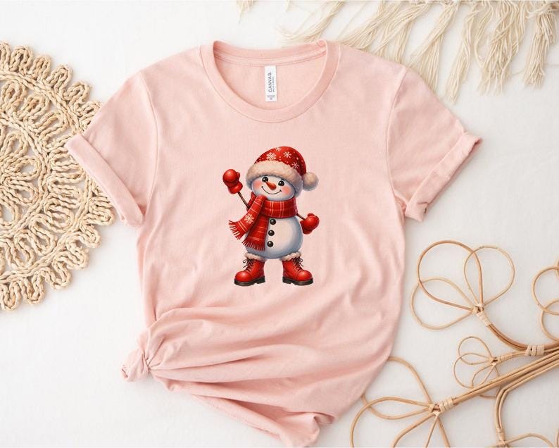 Pu&ograve; includere: T-shirt rosa chiaro con una grafica di pupazzo di neve allegro. Il pupazzo di neve indossa un cappello, una sciarpa, guanti e stivali rossi. La grafica &egrave; centrata sulla maglietta, creando un design festoso. La maglietta &egrave; in materiale morbido.