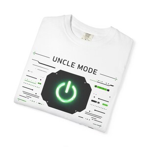 May include: White t-shirt with the text "UNCLE MODE" above a black and green graphic of a power button. The design includes green and black lines and shapes, giving it a tech-inspired look.