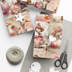 Puede incluir: Cajas de regalo envueltas con un diseño caprichoso con gansos con vestidos y sombreros, fresas y escritura vintage. El papel de regalo está atado con hilo y adornado con etiquetas en forma de estrella y corazón. También hay un ovillo de hilo y unas tijeras.