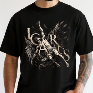 May include: Black t-shirt featuring a detailed illustration of Icarus, with outstretched arms and feathered wings. The design includes the word "ICARUS" in a stylized font, creating a dramatic and artistic aesthetic.