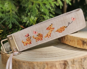 Schlüsselband aus Leinen in beige mit lustigen Hunden und Schmetterlingen bestickt – personalisierbar mit Name
