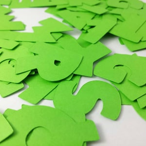 May include: A pile of bright green paper letters, scattered on a white surface. The letters are cut out in a simple, bold font.