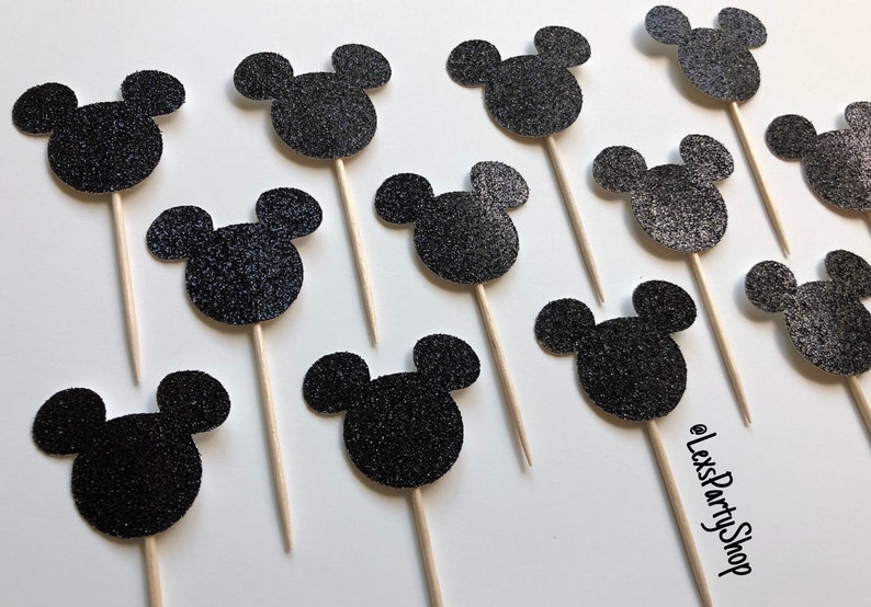 Pode incluir: Toppers para cupcake com cabe&ccedil;a de Mickey Mouse de glitter preto. Existem 12 toppers na imagem. Os toppers est&atilde;o em palitos de madeira.
