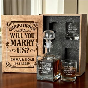 Può includere: Set di scatola in legno con una caraffa e due bicchierini. La scatola è incisa con "Christopher, Will You Marry Us?" e la data 07.13.2026. La caraffa e i bicchieri sono incisi con "Officiant Christopher" e la data 07.13.2020.
