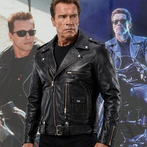 Könnte beinhalten: Eine schwarze Motorradlederjacke mit breitem Reverskragen, asymmetrischem Frontreißverschluss, mehreren Reißverschlusstaschen, einer kleinen Klappentasche mit Druckknopf und einem Gürtel mit Schnalle, getragen über einem schlichten schwarzen T-Shirt.