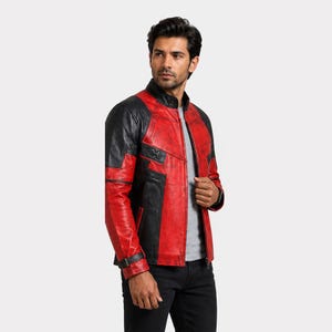 K&ouml;nnte beinhalten: Rote und schwarze Lederjacke mit Stehkragen. Die Jacke hat schwarze Eins&auml;tze an Schultern und &Auml;rmeln sowie rote Eins&auml;tze an Brust und Torso. Ein kleines Schnallendetail ist am linken &Auml;rmel sichtbar.