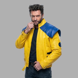 May include: A yellow leather jacket with blue shoulder pads and black stripe detailing. The jacket has a round patch with a blue and black design on the sleeve. The jacket has a black belt and a black collar.