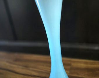 May include: A tall, light blue glass vase with a flared top and a rounded base. The vase has a slender, curved body and a contrasting darker blue base. The vase is approximately 10 inches tall.