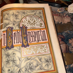 May include: Open book with a detailed, colorful illustration. The page features ornate floral and geometric designs in shades of gray, gold, red, and blue. The text "BETHLEHEM" is prominently displayed in a decorative font, suggesting a historical or religious theme.