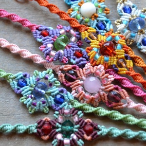 Puede incluir: Una colecci&oacute;n de pulseras de amistad coloridas con intrincados nudos y diversas cuentas, incluyendo cuentas rosas, moradas, verdes, azules, naranjas y blancas.