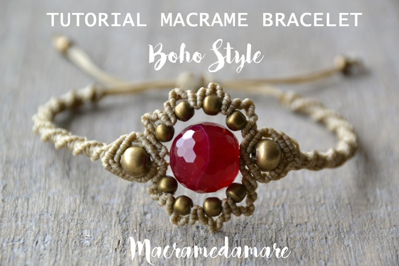 Puede incluir: Un brazalete de macram&eacute; con una piedra preciosa roja y cuentas doradas. El brazalete est&aacute; hecho con un cord&oacute;n beige y tiene un dise&ntilde;o de "estilo boho". El texto "Macramedamare" es visible en la parte inferior de la imagen.