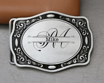 May include: Silver-toned belt buckle with a black border and ornate design. The buckle features a stylized letter "M" with the name "Mike" inscribed below it.