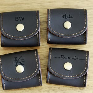 May include: Four brown leather pouches with a snap closure. Each pouch has a different personalized inscription: "BW", "Mike", "Kristen", and "Rachel".