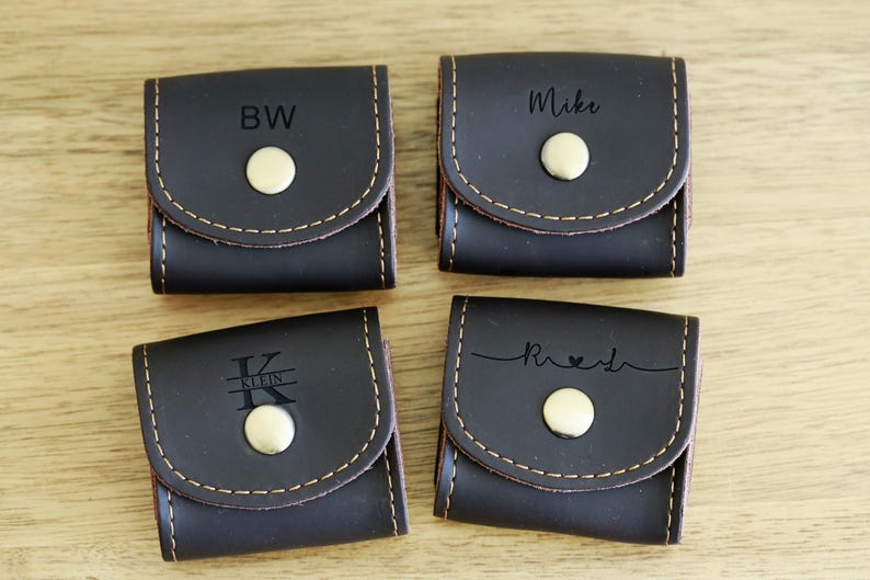 May include: Four brown leather pouches with a snap closure. Each pouch has a different personalized inscription: "BW", "Mike", "Kristen", and "Rachel".