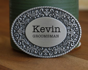 May include: Silver oval belt buckle with an ornate design and the text "Kevin GROOMSMAN" engraved on the front.