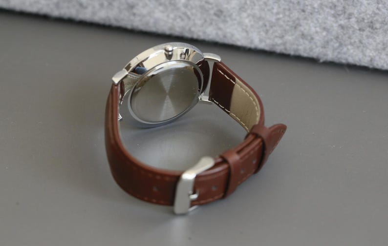 May include: A silver watch with a brown leather band. The watch face is not visible in the image.