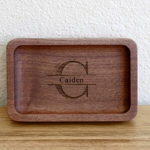 May include: A rectangular wooden tray with a raised edge. The tray is engraved with the letter "C" and the name "Caiden" underneath.