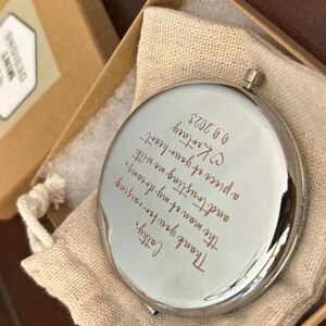 Op de afbeelding: Een zilveren compact spiegel met een handgeschreven bericht dat luidt: "Cattry, Dank je voor het opvoeden van de man van mijn dromen, en voor het vertrouwen dat je me geeft met een deel van je hart. Kartney 9.9.2023"