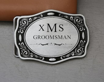 May include: Silver belt buckle with an ornate design and the text "XMS GROOMSMAN".