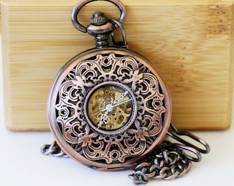 May include: A copper pocket watch with an intricate, ornate design and a visible clockwork mechanism. The watch has a chain attached.