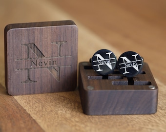 May include: A pair of black cufflinks with a white engraved letter N and the name "Nevin" on each cufflink. The cufflinks are in a wooden box with a lid that has the same engraved letter N and name.