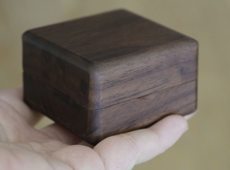 May include: A dark brown wooden box with a hinged lid. The box is made of a dark wood with a natural grain pattern.