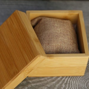 Puede incluir: Una caja de madera con tapa, la caja est&aacute; abierta y el interior est&aacute; forrado con una tela marr&oacute;n. La caja es de madera marr&oacute;n claro.